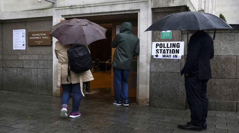 People queue in the rain outside a polling station for the Referendum on the European Union in north London, Britain, June 23, 2016. 