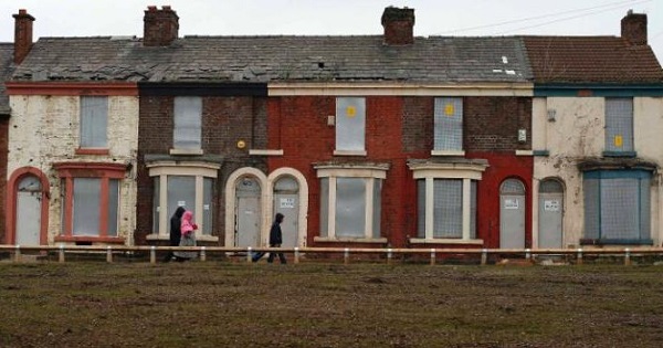 People walk past a row of boarded up terraced houses in Liverpool in 2013.