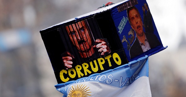 A demonstrator holds up a placard depicting Argentina's Macri with the word 