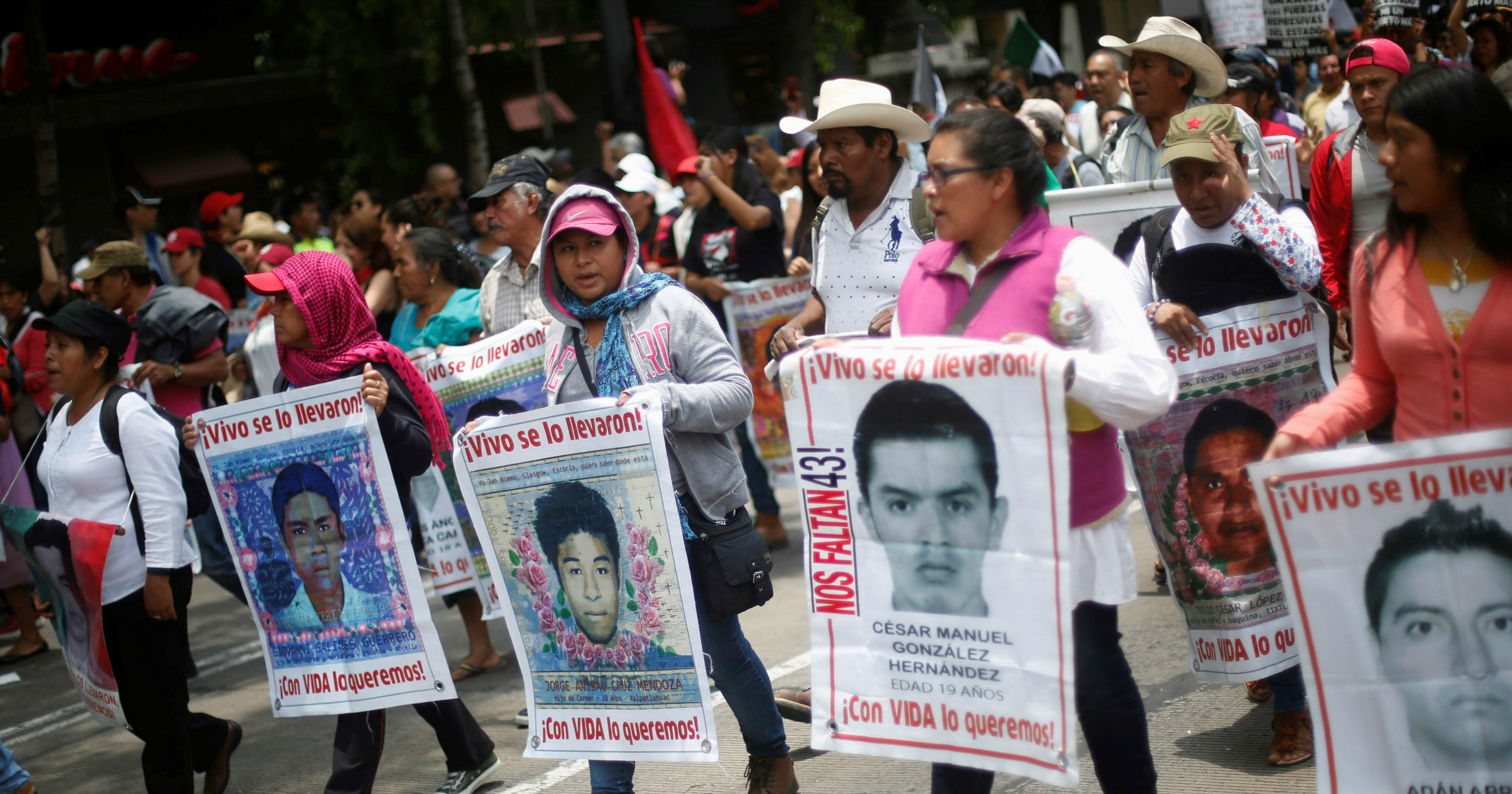 Relatives hold posters with images of some of the 43 missing students as they protest to demand justice for the missing students during a march to mark the 21-month anniversary of their disappearance, in Mexico City, Mexico, June 26, 2016.