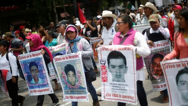 Relatives hold posters with images of some of the 43 missing students as they protest to demand justice for the missing students during a march to mark the 21-month anniversary of their disappearance, in Mexico City, Mexico, June 26, 2016.