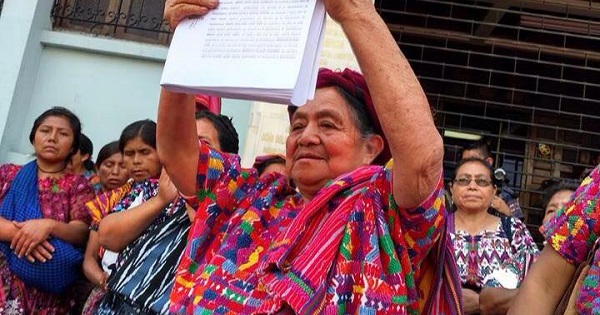 An Indigenous women holds up the case presented to the court for intellectual property rights over Mayan textiles.