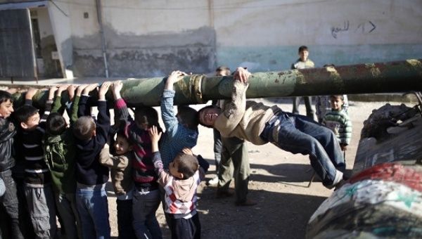 Children hang from the barrel of a tank, which was captured by the Free Syrian Army, in Azaz city, north Aleppo, Syria.