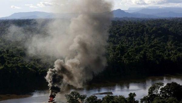 An illegal gold dredge is seen burning down at the banks of Uraricoera River during an operation by Brazil’s environmental agency against illegal gold mining on Indigenous land.