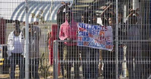 African migrants gesture behind a fence inside Holot, Israel's new Negev desert detention center.