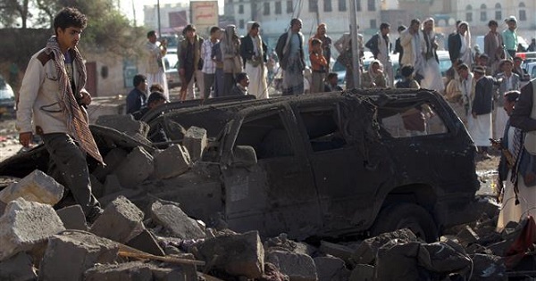 Yemenis stand at the site of a Saudi air strike against Houthi Ansarullah fighters near Sana’a Airport, Yemen, on March 26, 2015