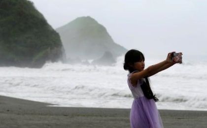 Waves are seen behind a girl as Typhoon Nepartak approaches, in Yilan, Taiwan July 7, 2016.