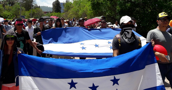 Masked student protesters carry the Honduran flag during massive marches against the privatization of education in Tegucigalpa, July 10, 2016.