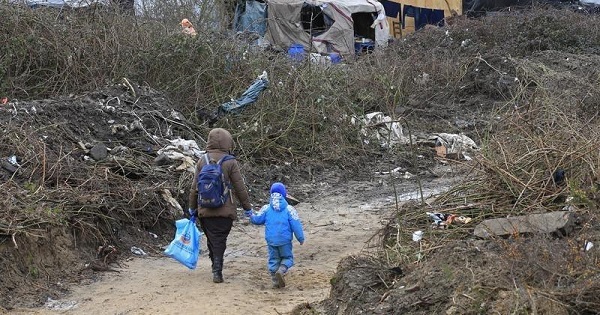 A migrant and her child walk in the southern part of a camp for migrants called the 