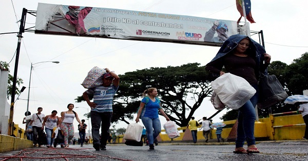 People are seen carrying bags and packages as they cross the Colombian-Venezuelan border.