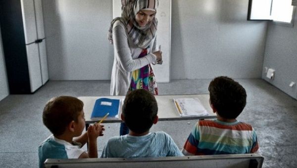 A teacher gives English lessons to children in a container converted into a classroom on June 24, 2016 at the refugee camp of Skaramangs, south of Athens.