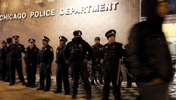 A file photo shows a protester walking past a line of police officers standing guard in front of the District 1 police headquarters in Chicago, Illinois November 24, 2015.