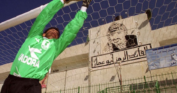 A Palestinian goalkeeper practices fielding shots in a file photo at the Gaza soccer stadium where a large mural of Palestinian President Yasser Arafat hangs behind the goal.