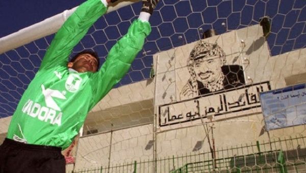 A Palestinian goalkeeper practices fielding shots in a file photo at the Gaza soccer stadium where a large mural of Palestinian President Yasser Arafat hangs behind the goal.