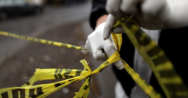 A forensic technician ties a used police line together to seal off a crime scene in Monterrey Feb. 8, 2012.
