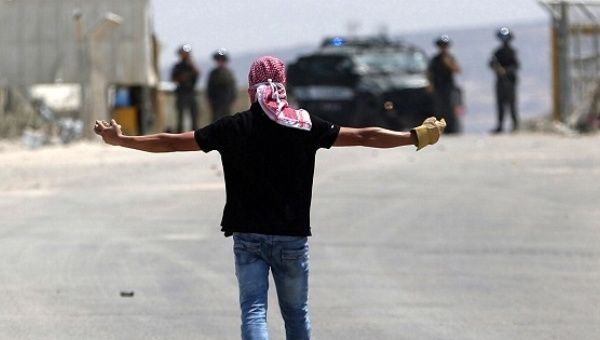 A Palestinian protester gestures in front of Israeli troops during clashes near Israel's Ofer Prison near the West Bank city of Ramallah August 3, 2016.