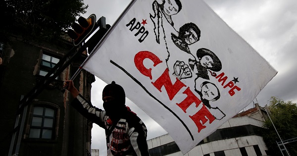 A man holds up a flag ahead of protesters from the CNTE teachers’ union as they march against education reform, along the streets in Mexico City, July 19, 2016.
