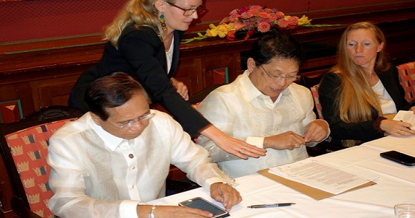 Philippine government negotiators Jesus Dureza (L) and Silvestre Bello sign an indefinite ceasefire agreement with communist rebels at a meeting in Oslo, Norway, August 26, 2016.