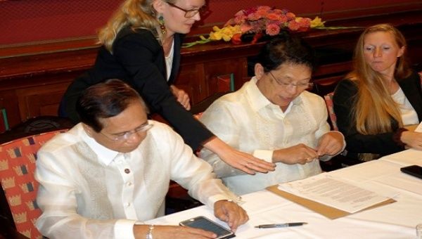 Philippine government negotiators Jesus Dureza (L) and Silvestre Bello sign an indefinite ceasefire agreement with communist rebels at a meeting in Oslo, Norway, August 26, 2016. 