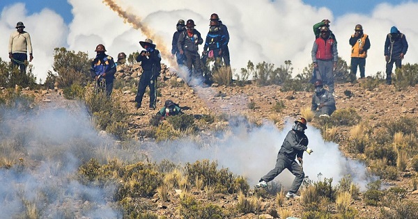 An miner returns a tear gas canister during clashes with riot police during a protest against government policies, in Panduro south of La Paz, Bolivia, Aug. 25, 2016.