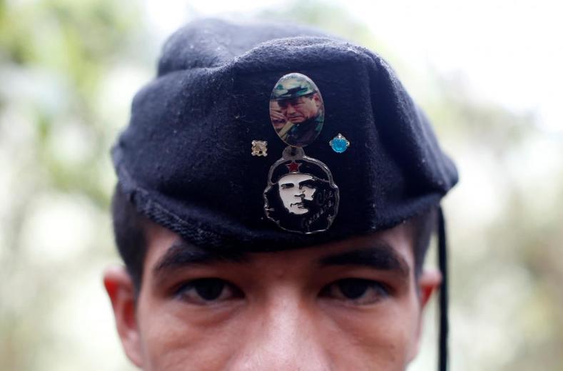 Eduar, a member of the 51st Front of the FARC, is seen wearing a cap with badges showing images of Che Guevara and FARC's late founder Manuel Marulanda at a camp in the Colombian mountains.