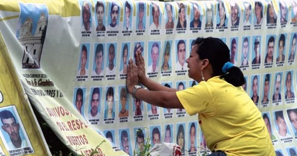A woman cries in front of photographs of disappeared family members in Medellin, Colombia, March 15, 2013.