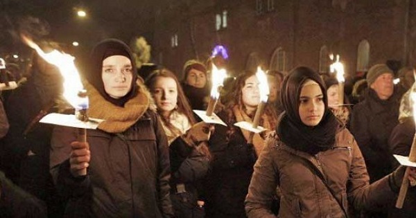 People hold candles during a memorial service for victims killed by a gunman in Copenhagen, Denmark, February 2015.
