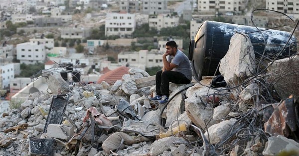 A Palestinian man sits atop the rubble of a house which was destroyed by Israeli troops during an Israeli raid in the West Bank city of Jenin, Sept. 1, 2015.