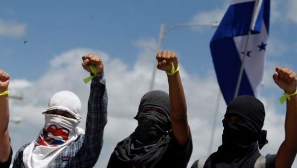 Masked students of UNAH raise their hands during a protest in Tegucigalpa, Honduras, July, 2016.