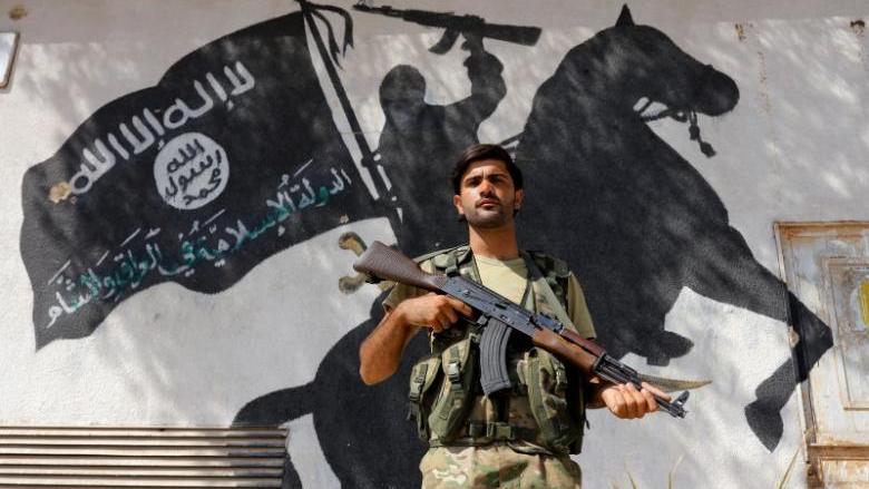 A member of Turkish-backed Free Syrian Army (FSA), seen with a mural of the Islamic State in the background, stands guard in front of a building in the border town of Jarablus, Syria, August 31, 2016.