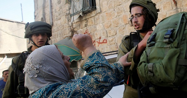 A Palestinian woman argues with Israeli soldiers as they detain her relative in the West Bank city of Hebron Sept. 20, 2016.