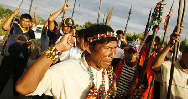 A group of Indigenous people brandish spears while blocking a highway in Peru's Amazonian region.