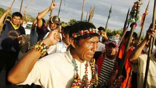 A group of Indigenous people brandish spears while blocking a highway in Peru's Amazonian region. 