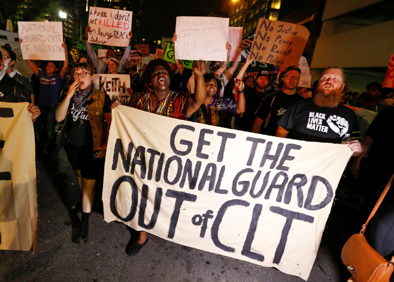 Marchers hold a sign asking for the removal of National Guard troops during a protest against the police shooting of Keith Scott, in Charlotte, North Carolina, U.S. Sept. 22, 2016.