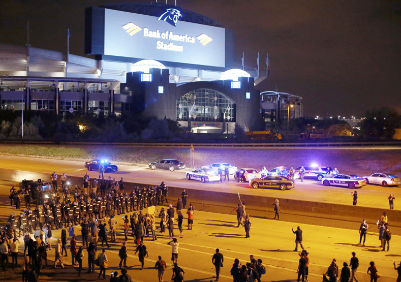 Riot police push protesters off the highway during another night of protests over the police shooting of Keith Scott in Charlotte, North Carolina, Sept. 22, 2016. 