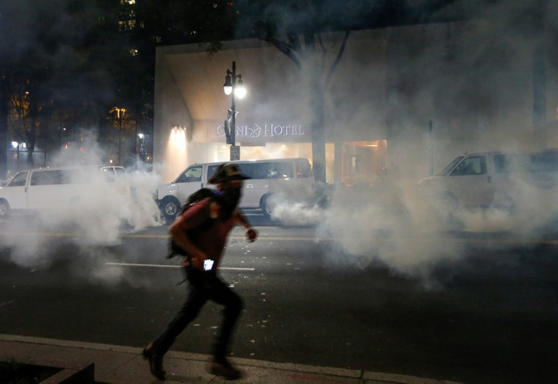 A man runs from tear gas in uptown Charlotte, NC during a protest of the police shooting of Keith Scott, in Charlotte, North Carolina, Sept. 21, 2016.