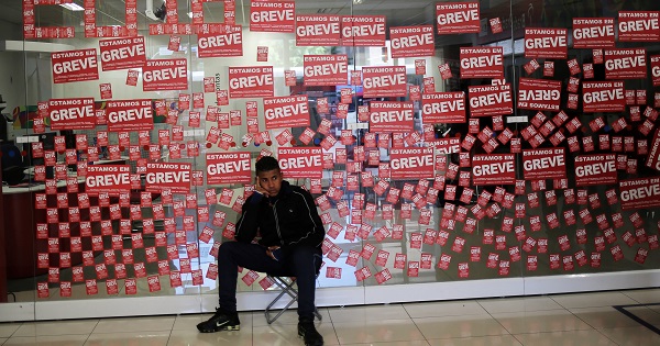 A man sits in front of posters reading 