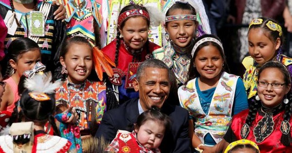President Obama holds a baby as he poses with children at the Cannon Ball Flag Day Celebration at the Standing Rock Sioux Reservation in North Dakota.