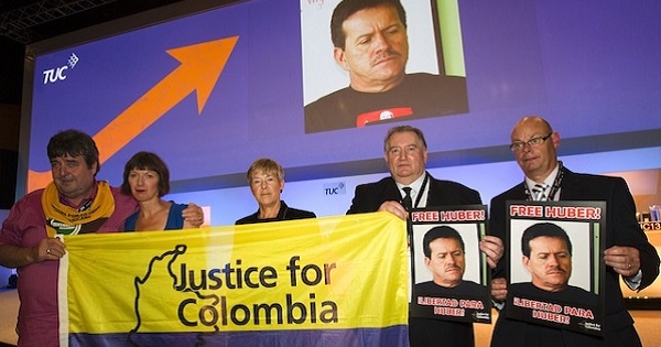 Justice for Colombia members in the U.K. hold images of Huber Ballesteros at forum calling for his freedom.