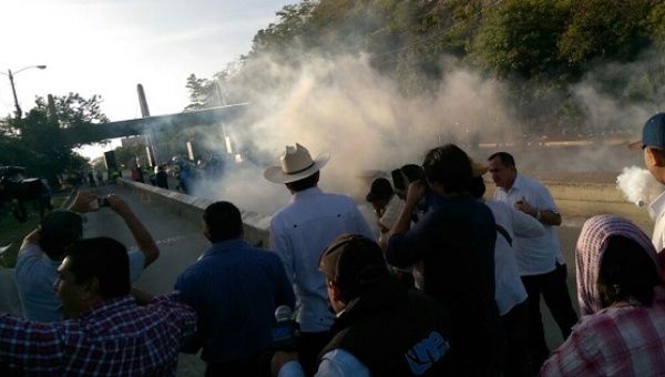Smoke from tear gas blows in front of protesters near San Pedro Sula, who are demonstrating against new tolls.