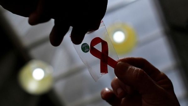 Nurse gives a red ribbon to a woman to mark World Aids Day at the entrance of Emilio Ribas Hospital, in Sao Paulo.