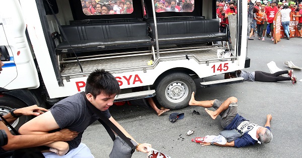 Protesters lie on the ground after being hit by a police van during the protest outside the U.S. embassy in Manila, Wednesday.