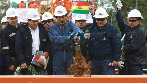 Bolivian President Evo Morales (C) turns on the tap at the new oil reserve discovered earlier this year.
