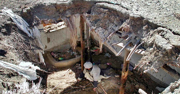 A Pakistani tribesman sifts through the rubble of his house after an attack in January 2006.