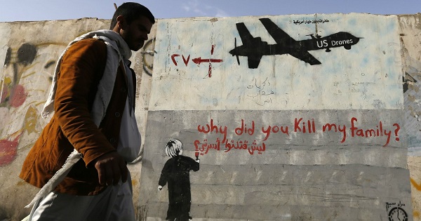 A man walks past a graffiti denouncing strikes by U.S. drones in Yemen.