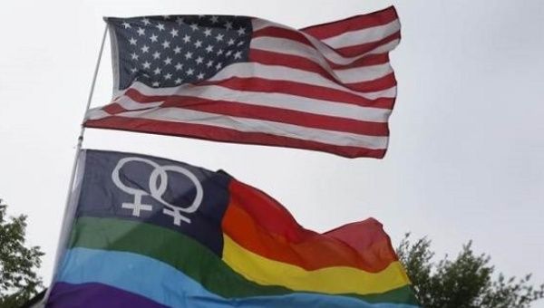 A Gay Pride flag flies below the U.S. flag during a celebration of the U.S. Supreme Court's landmark ruling of legalizing gay marriage nationwide, at a rally in Ann Arbor, Michigan, June 26, 2015. 