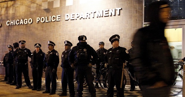A protester walks past a line of police officers standing guard in front of the District 1 police headquarters in Chicago, Illinois November 24, 2015.