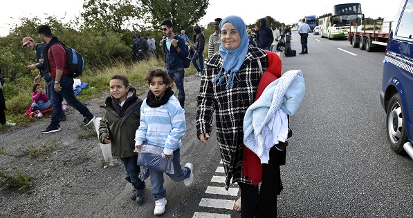 A group of migrants, mainly from Syria, walk along a highway in Denmark.