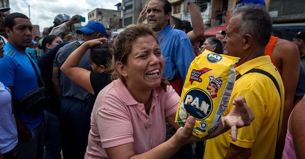 A distraught woman holds up a bag of Pan cornflour, a staple of the Venezuelan diet made by the Polar Company, Caracas, Venezuela, June 11, 2016.