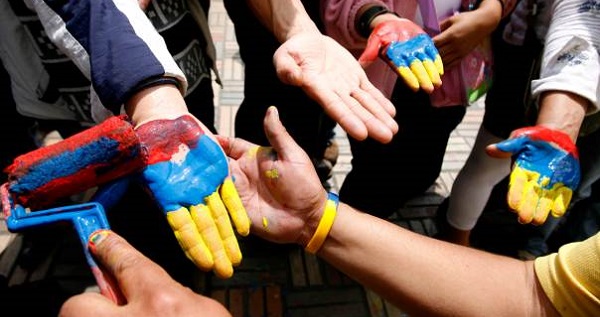 In a 2008 file photo, a man paints hands the colors of the Colombian flag during a protest in Bogota against paramilitary right-wing violence.